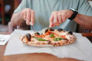 Close-up shot of a man eating pizza in an Italian restaurant, showcasing vibrant toppings.