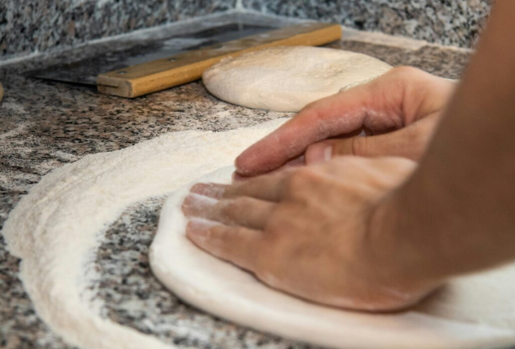 Close-up of hands kneading dough on a floured kitchen countertop.